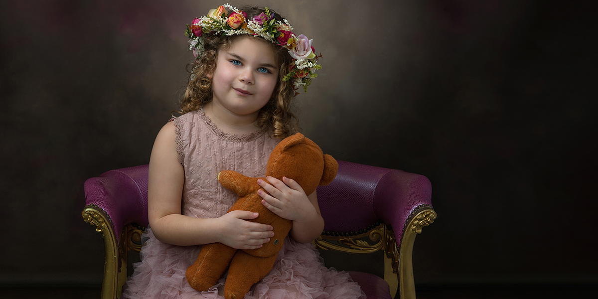 portrait of child wearing pink dress, holding teddy bear