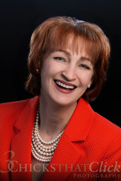 professional headshot of woman wearing a red jacket and pearl necklace